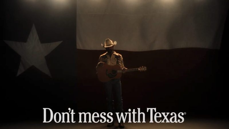 Post Malone standing in front of a giant Texas flag. The "Don't mess with Texas" logo is at the bottom of the image.